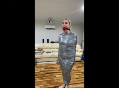 Aussie Bondage Girl – Tapped up in silver tape, hopping around the room and then stuck on the bed being vibed